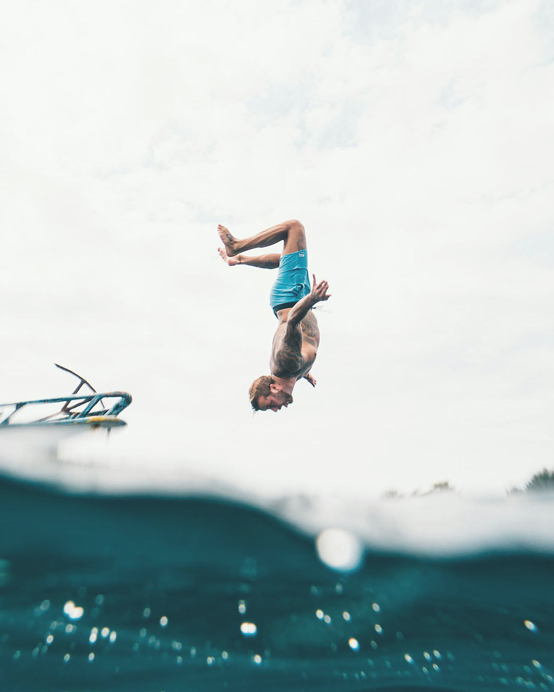 Person diving into water from a diving board with a clear sky background