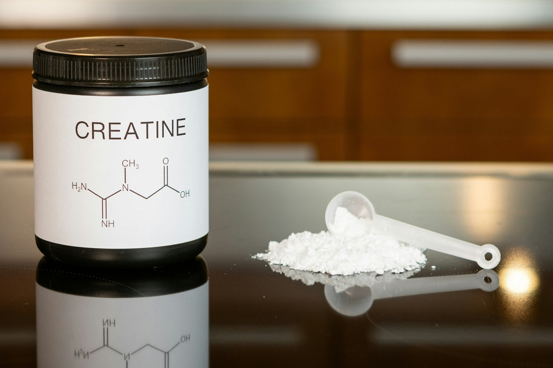 Creatine jar on a table with some creatine monohydrate powder next to it.