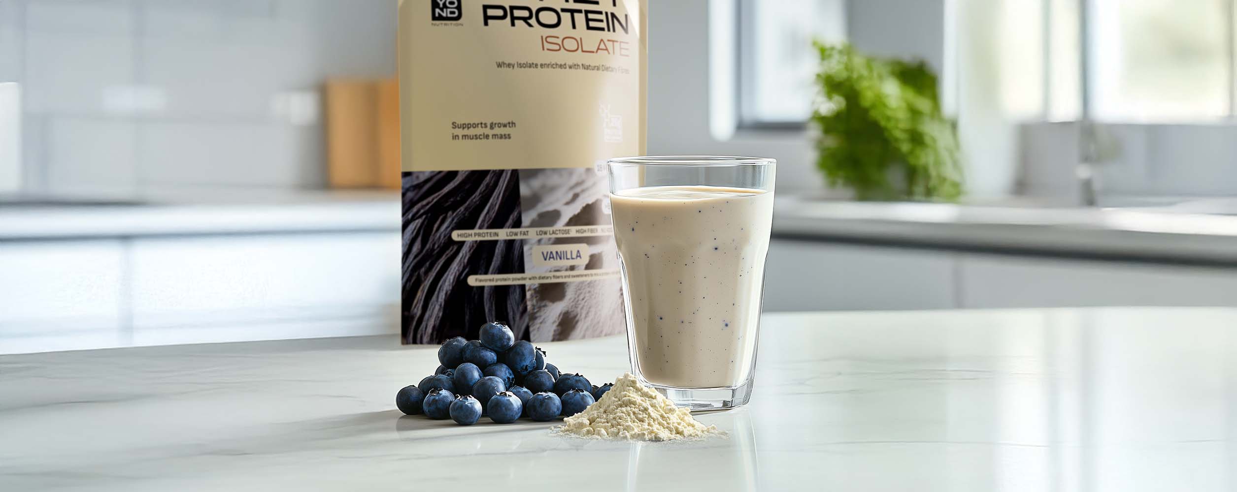 Protein powder container with a glass of protein shake and blueberries on a kitchen counter.
