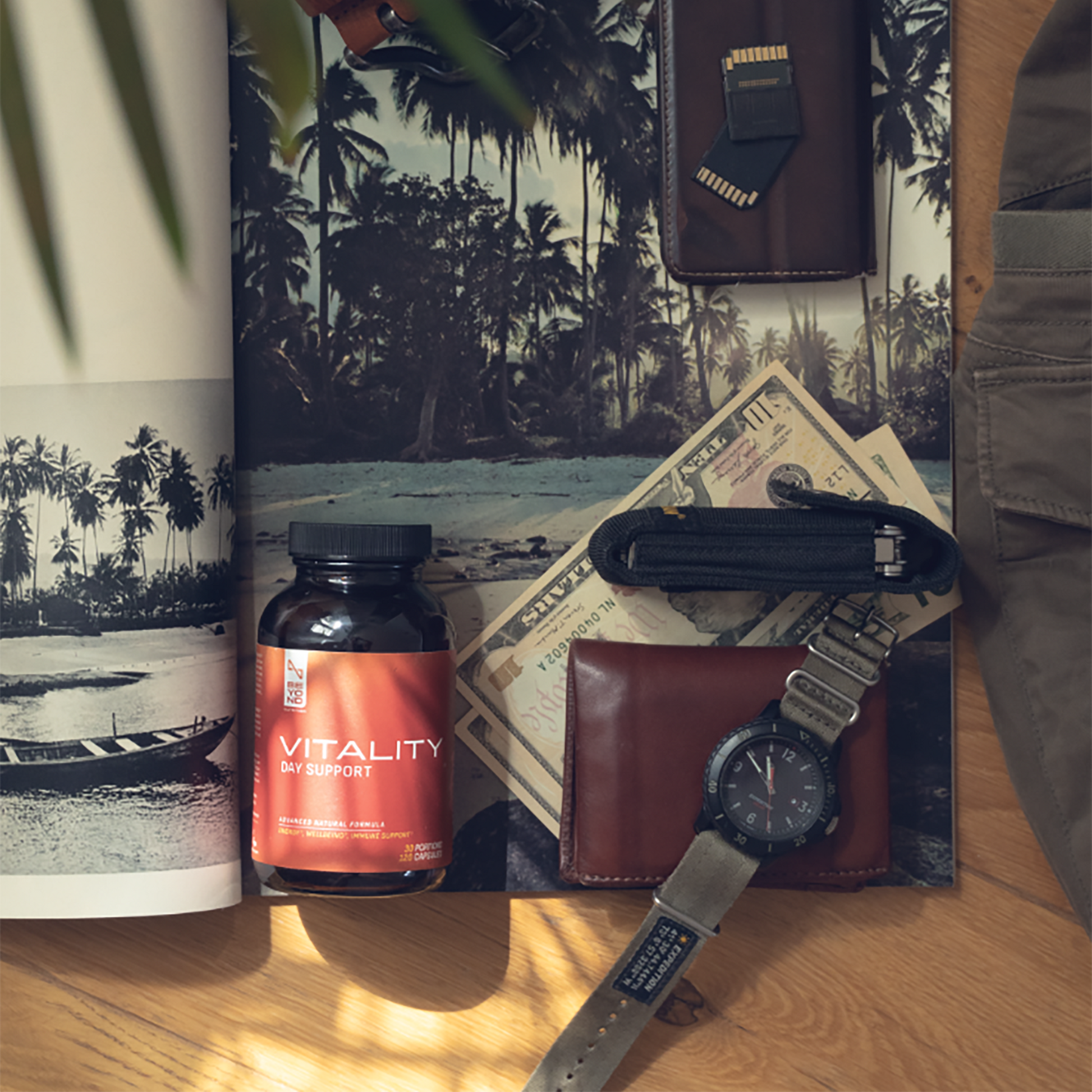Tabletop with a bottle labeled 'Vitality', wallet, watch, and money on a scenic background