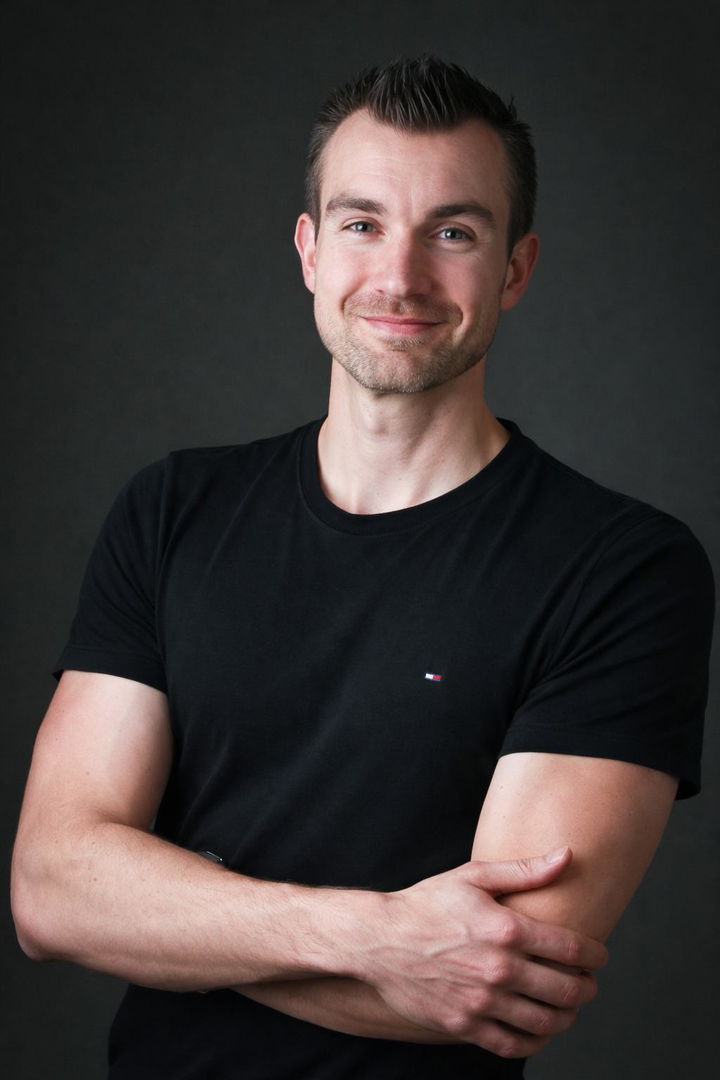 Man wearing a black t-shirt with a small logo on a dark background
