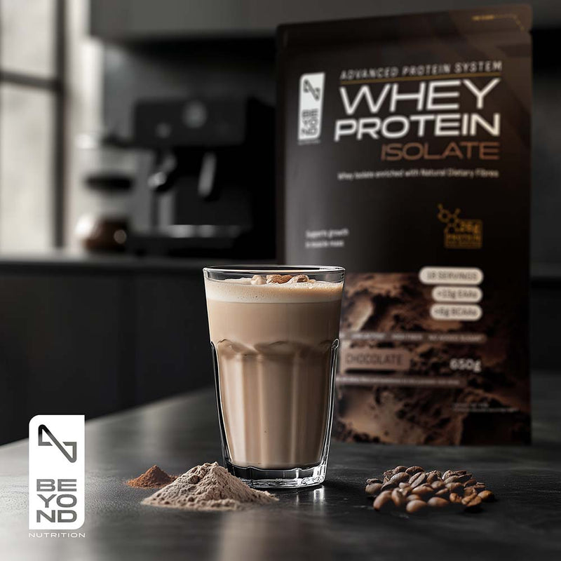 Glass of chocolate protein shake with whey protein isolate package in the background