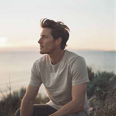 Man sitting on a beach at sunset